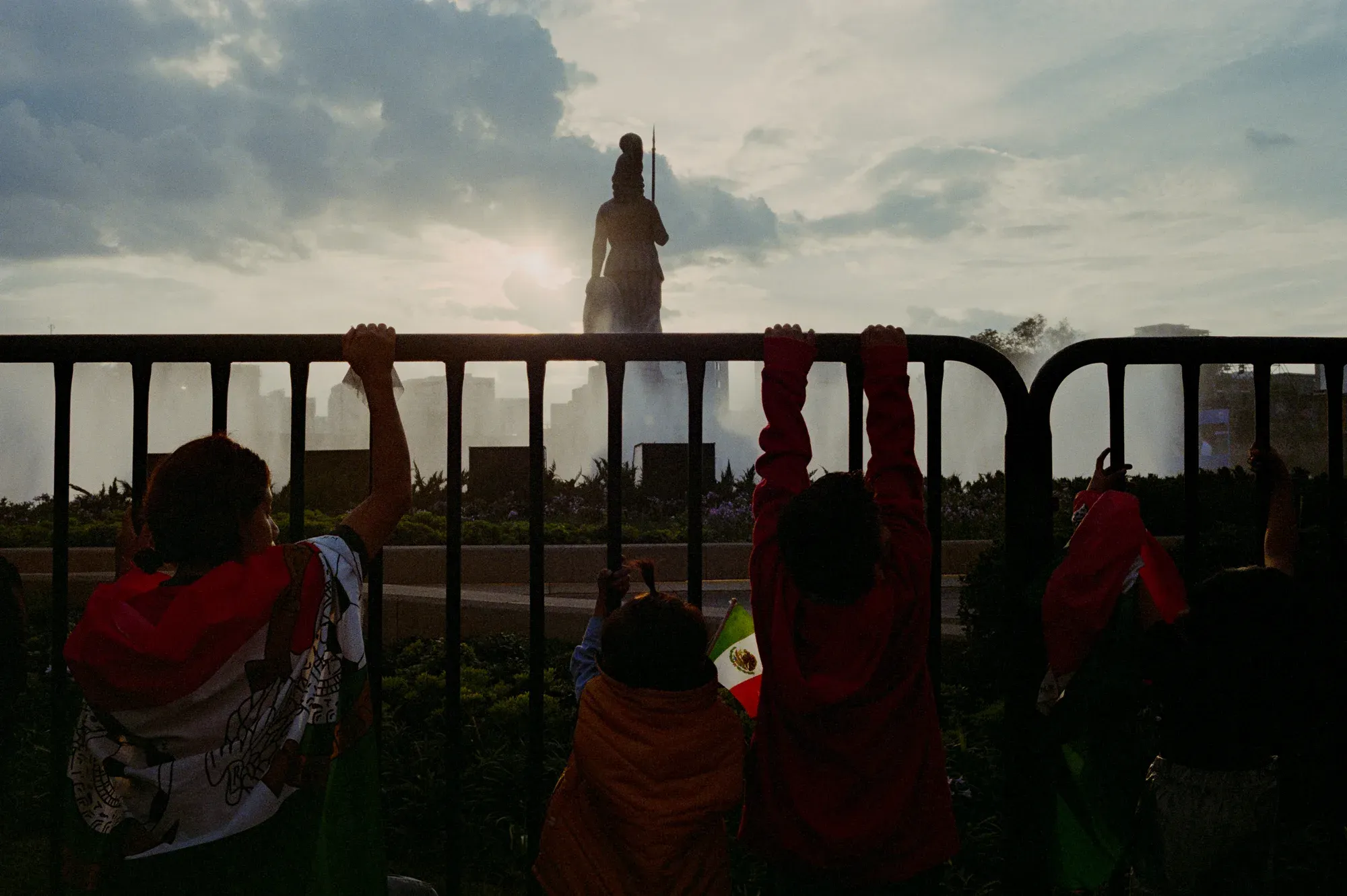 Familias asomadas a una valla mirando el monumento a la Minerva al atardecer