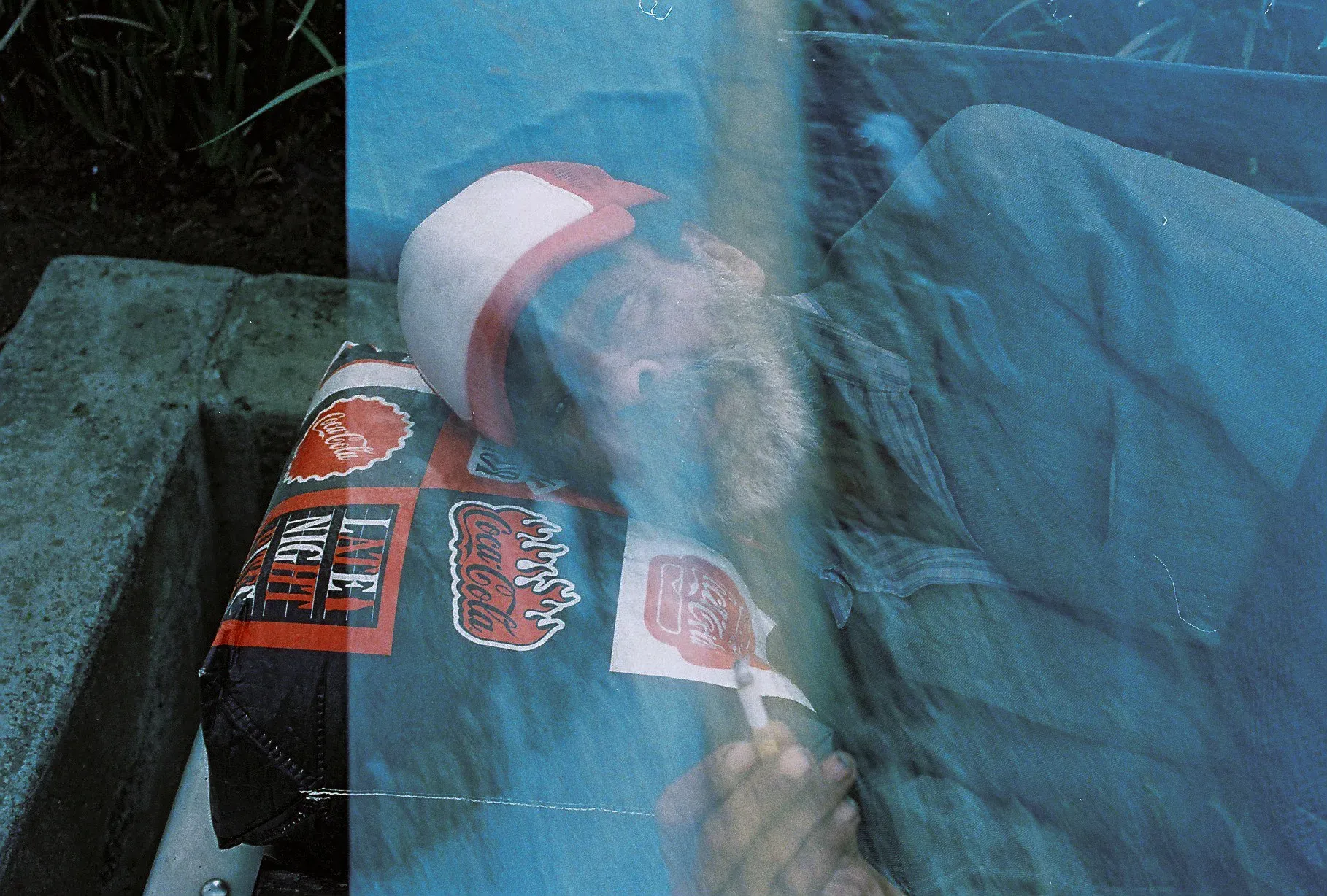 Reflejo en un cristal: hombre de gorra recostado entre calcomanías