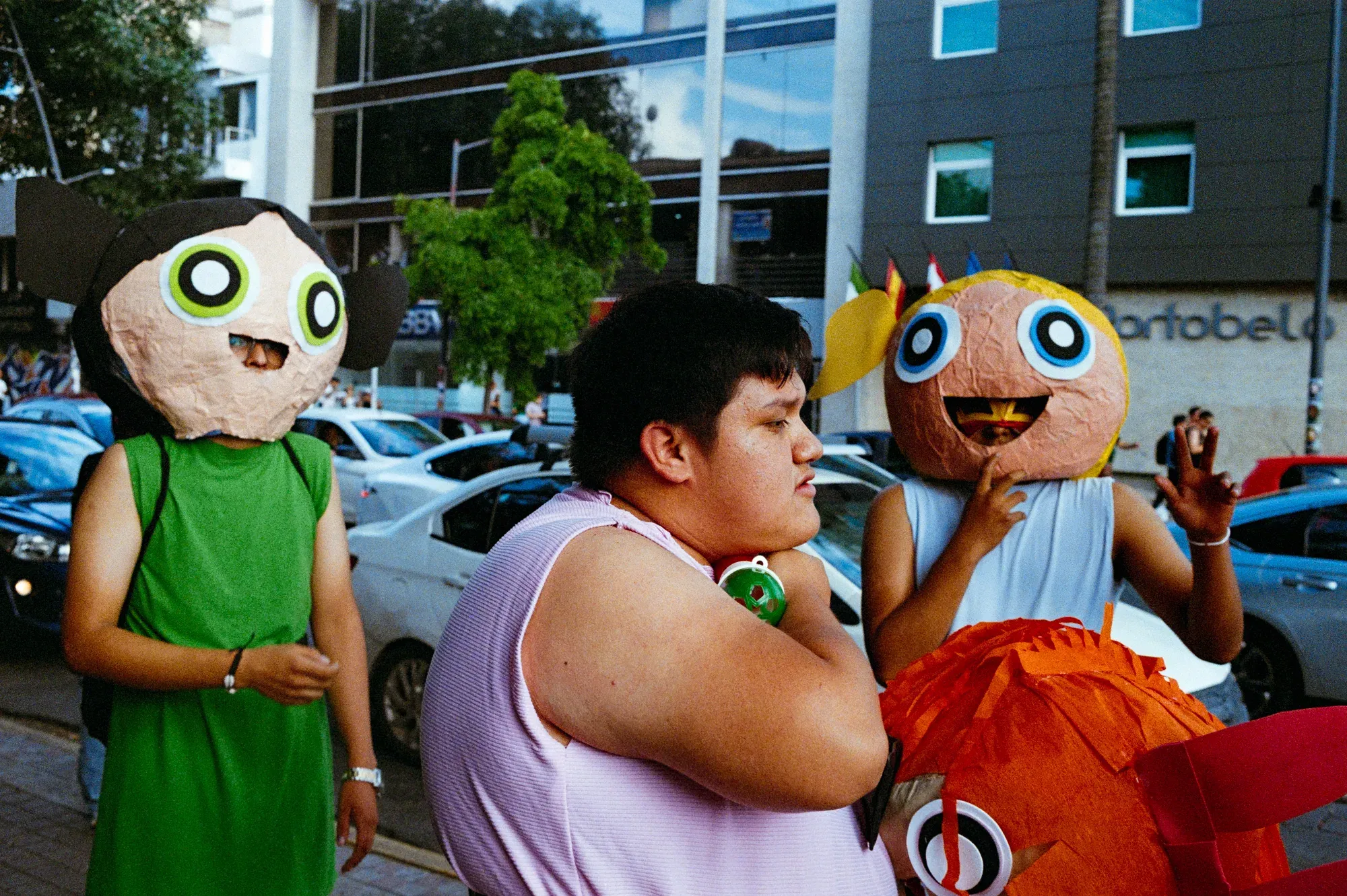 Tres jóvenes en la calle con máscaras de cartón de personajes de dibujos animados